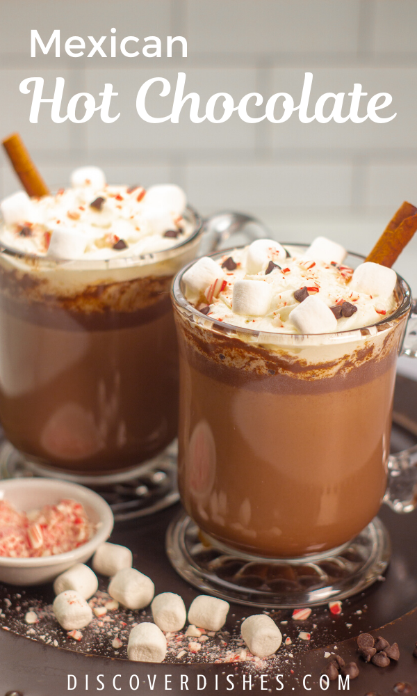 Mexican hot chocolate with marshmallows and cinnamon sticks on a serving tray.